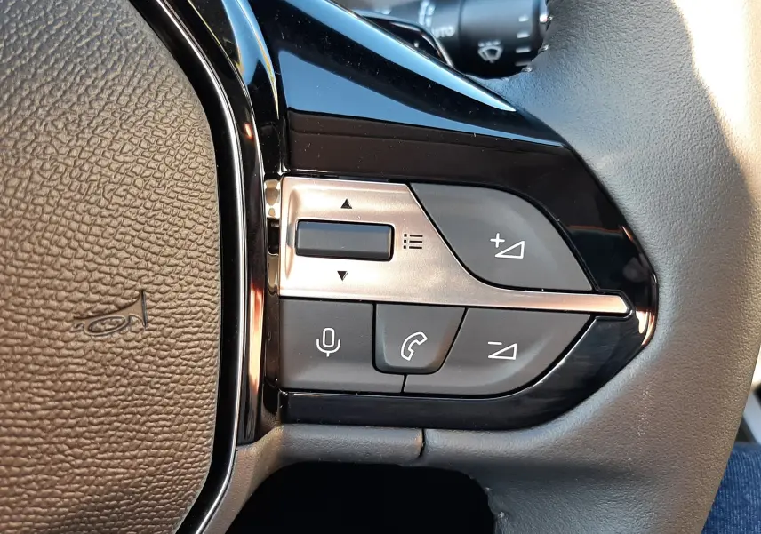 Gros plan sur les commandes du volant côté droit d'une Peugeot 308 Bleu Obsession 2025, avec boutons de volume et téléphone.