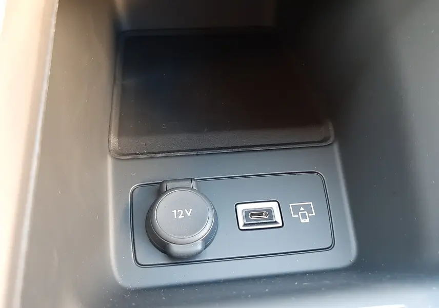 Prise 12V et port USB-C en gros plan dans la console centrale du Peugeot 308 Bleu Obsession 2025.