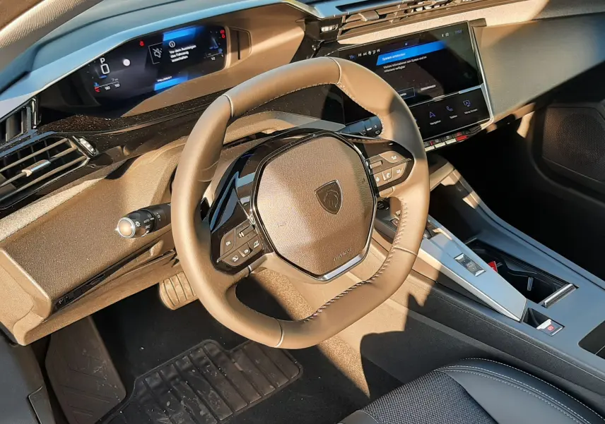 Intérieur Peugeot 308 2025 vue côté conducteur, volant compact, tableau de bord numérique et écran tactile central.