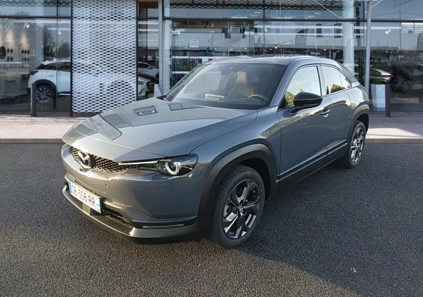 Vue 3/4 avant d'une Mazda MX-30 gris électrique 2021, avec ses phares ronds distinctifs et jantes noires.
