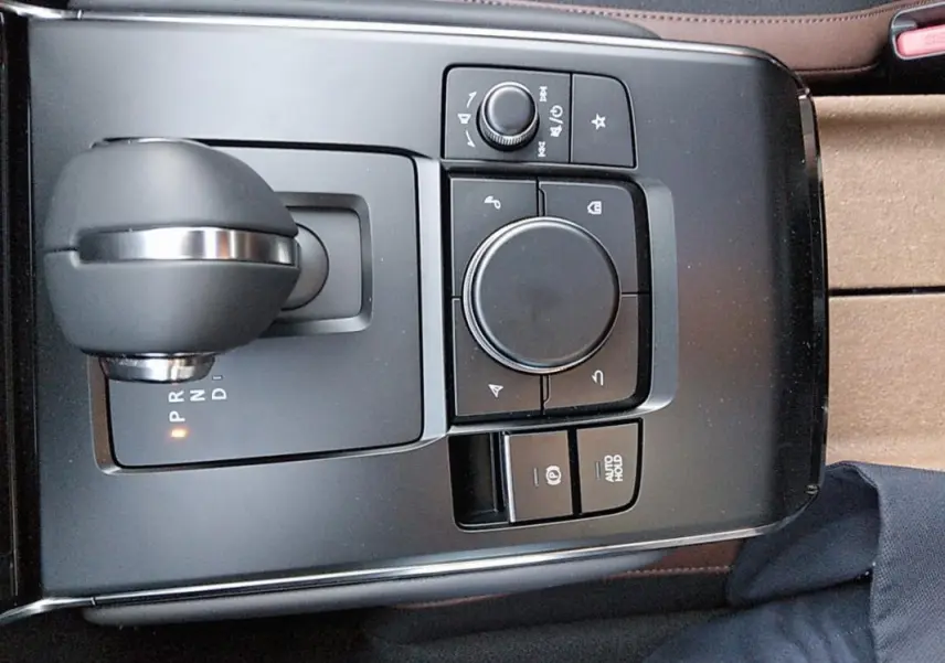 Vue plongeante sur la console centrale grise du Mazda MX-30 électrique 2021, avec levier de vitesses et commandes multimédia.