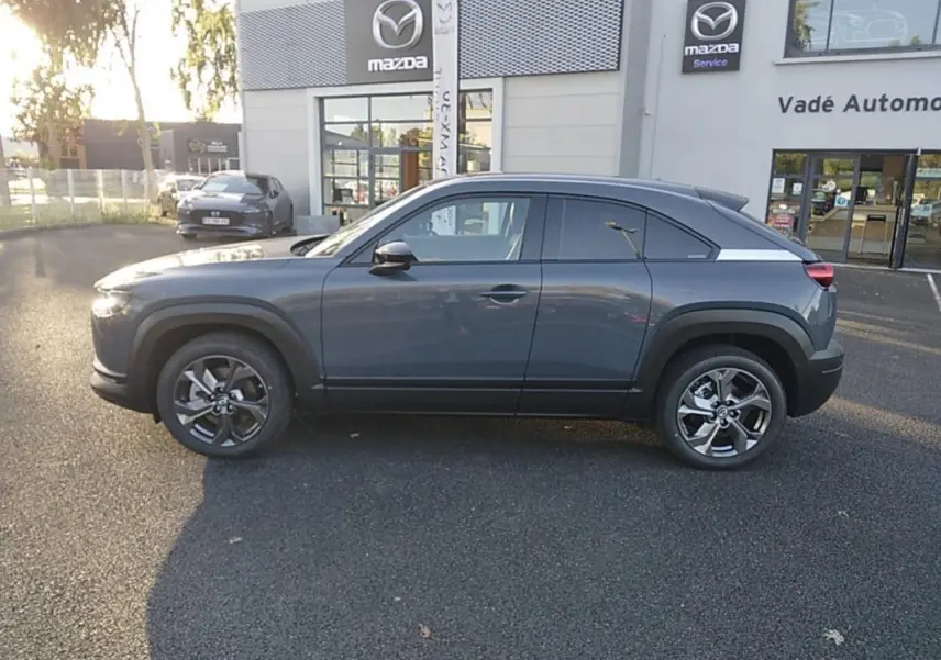 Vue de profil côté gauche d'un Mazda MX-30 gris électrique 2021, avec jantes alliage et toit légèrement incliné.