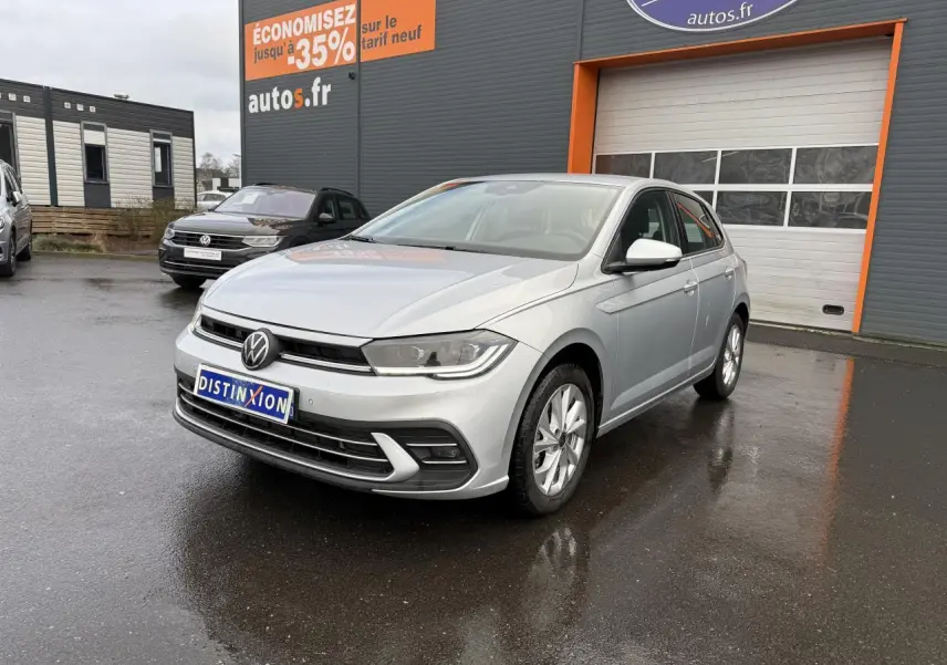 Volkswagen Polo 1.0 TSI Style argent métallisé vue 3/4 avant sur parking devant un garage autos.fr