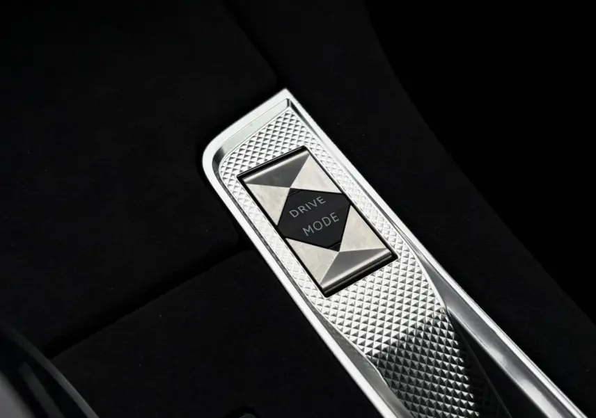 Gros plan sur le sélecteur de mode de conduite en métal brossé dans la console centrale noire du DS7 gris laqué.