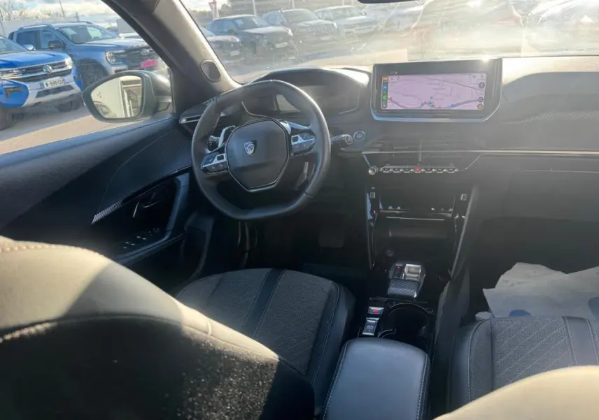 Vue intérieure avant gauche du Peugeot 2008 Hybrid 136 e-DCS6 Allure 2024, avec écran tactile et volant multifonctions.