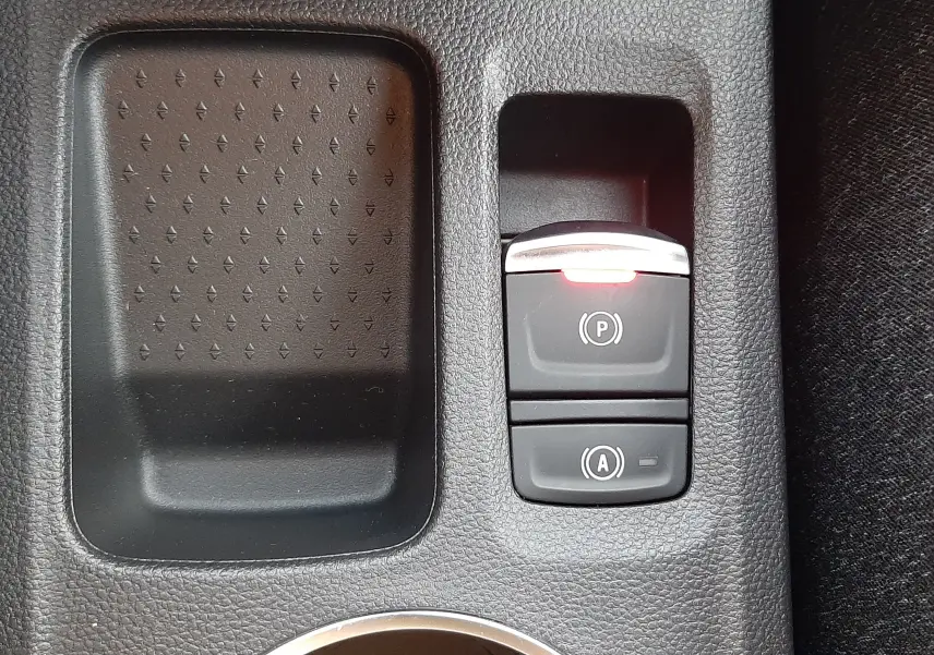 Gros plan sur la console centrale du Renault Captur bleu Iron 2025, montrant les commandes du frein à main électrique et de l'arrêt automatique.