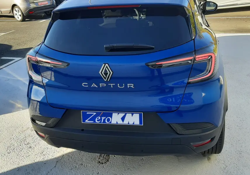 Vue arrière d'un Renault Captur bleu Iron 2025 avec feux LED et plaque d'immatriculation Zéro KM visible.