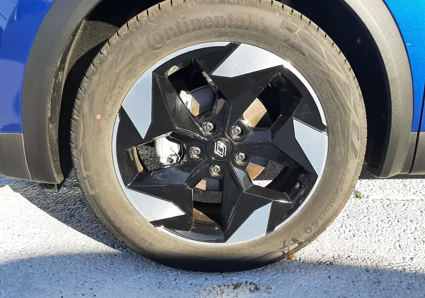 Gros plan sur la roue avant gauche du Renault Captur bleu Iron 2025 avec jante noire et argentée au design géométrique.