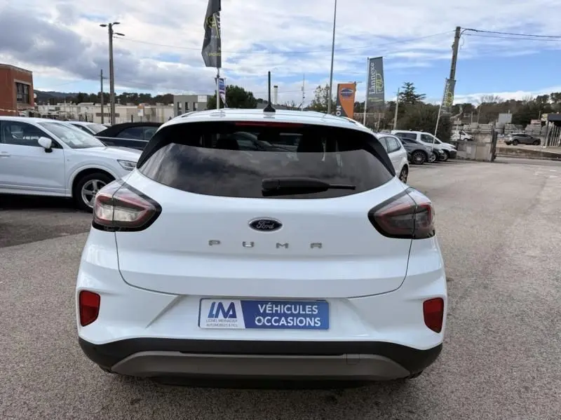 Vue arrière d'une Ford Puma blanche 2026 avec feux arrière fumés et logo PUMA bien visible, stationnée en extérieur.