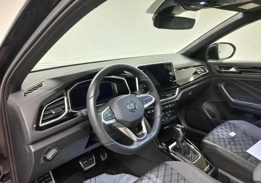 Vue intérieure côté conducteur du Volkswagen T-Roc 1.5 TSI R-Line 2025 noir intense avec volant multifonction et écran tactile central.
