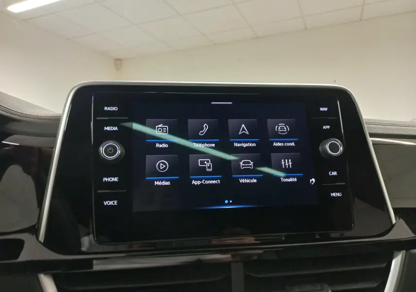Écran tactile central du Volkswagen T-Roc 2025 affichant les menus radio, téléphone, navigation et aides à la conduite.