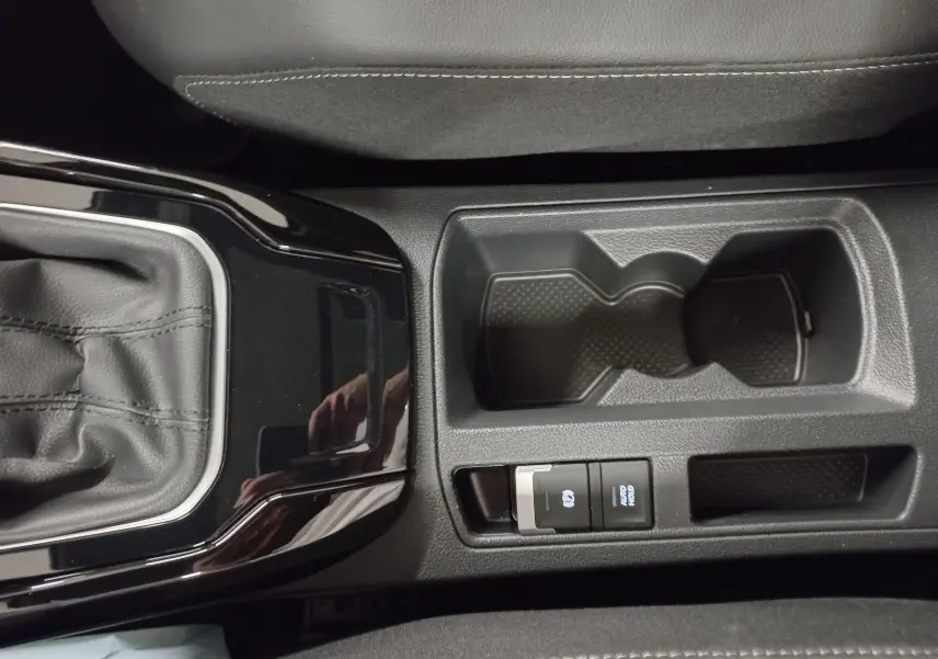Gros plan sur la console centrale noire du Volkswagen T-Roc 2025, avec levier de vitesses et porte-gobelets.
