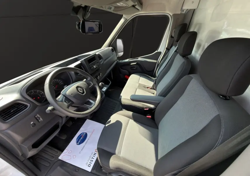 Vue intérieure côté conducteur du Renault Master 2024, sièges gris et tableau de bord noir avec volant multifonction.