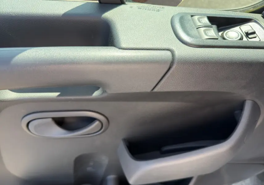 Gros plan sur la porte intérieure côté conducteur du Renault Master 2024, avec commandes électriques et poignée noire.