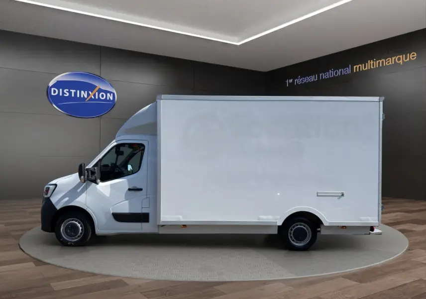 Vue de profil côté gauche d’un utilitaire Renault Master blanc avec caisse fermée, présenté en intérieur showroom.