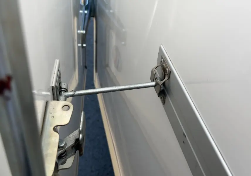 Gros plan sur le mécanisme d’ouverture de la porte latérale d’un Renault Master blanc, vue rapprochée côté droit.