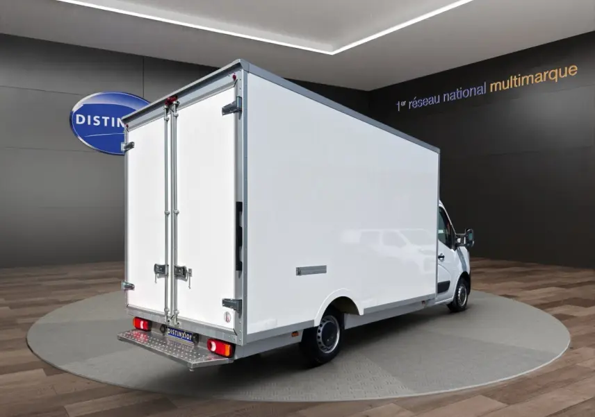 Renault Master blanc vu en 3/4 arrière droit, avec caisse fermée volumineuse et portes arrière battantes.
