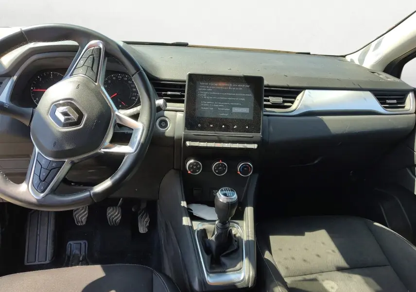 Vue intérieure avant du Renault Captur gris Cassiopée 2021, montrant le volant, la console centrale avec écran tactile et levier de vitesse manuel.