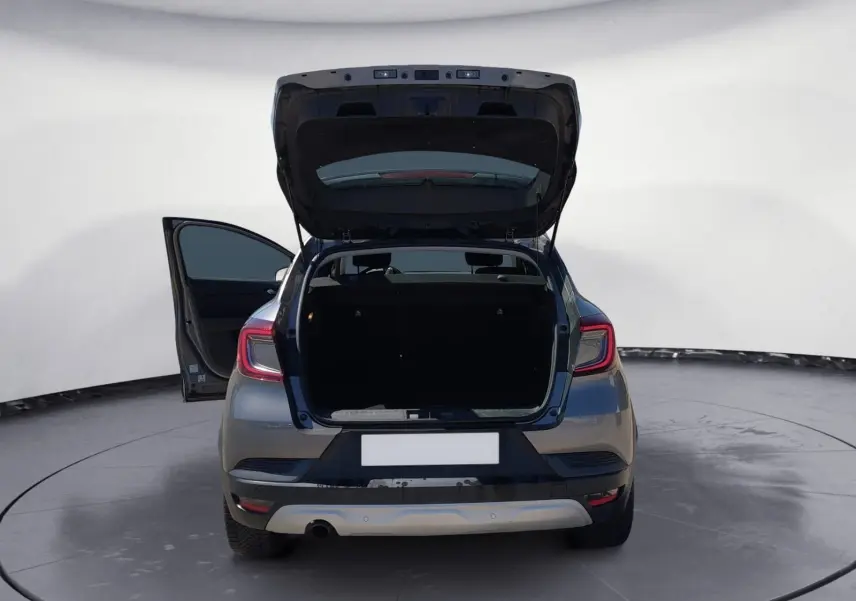 Vue arrière d'un Renault Captur gris Cassiopée 2021 avec coffre et porte côté gauche ouverts, mettant en valeur l'espace de chargement.