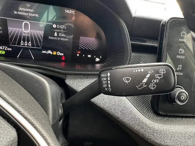 Vue rapprochée du commodo d’essuie-glace dans l’habitacle noir de la Skoda Scala blanc cristal, avec tableau de bord digital en arrière-plan.