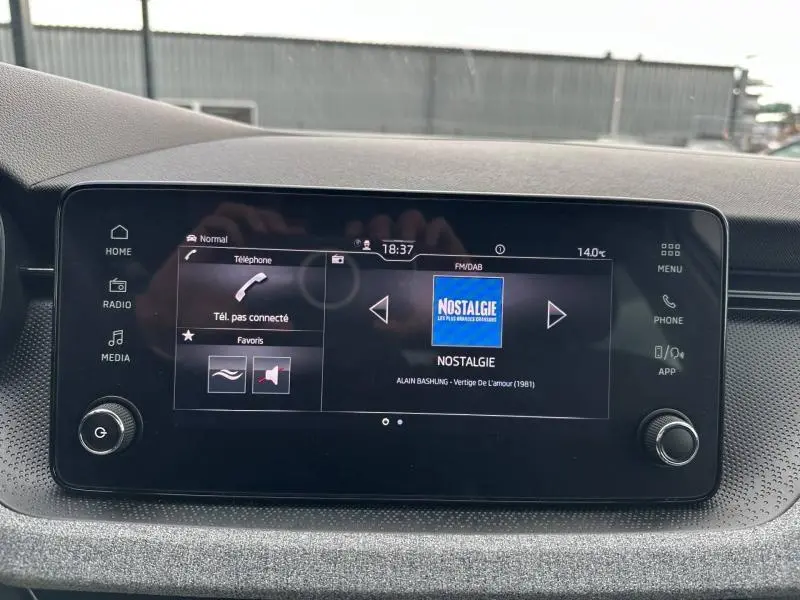 Écran tactile central de la Skoda Scala blanc cristal, affichant la radio FM/DAB sur la station Nostalgie.