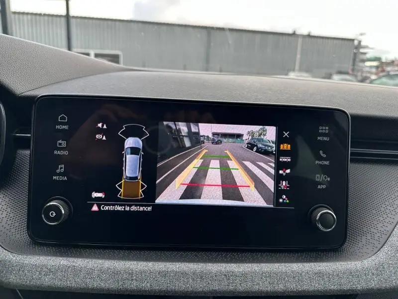 Écran tactile intérieur montrant la caméra de recul et l'alerte de distance du Skoda Scala blanc cristal.