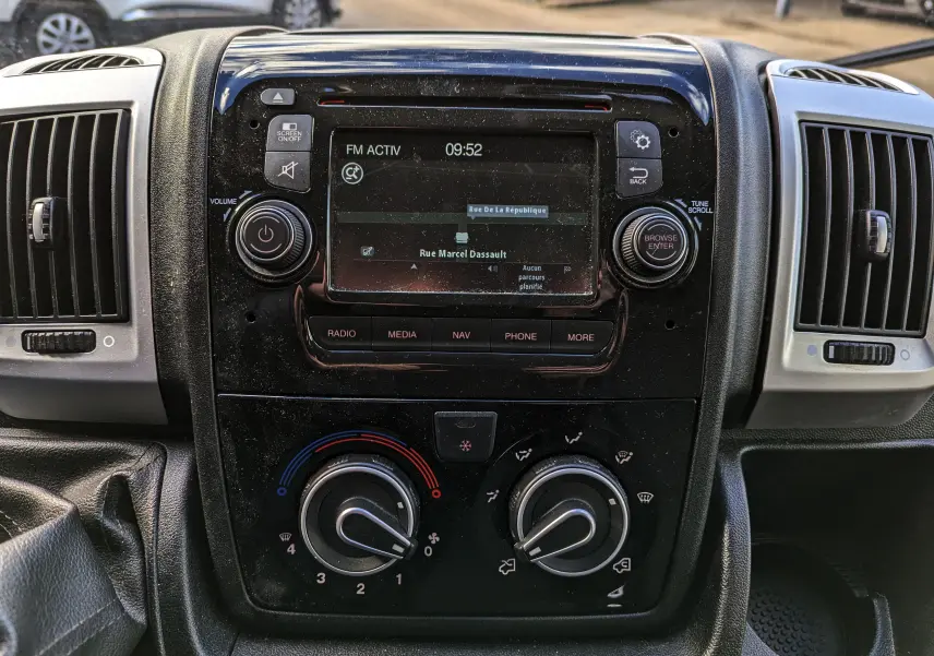 Vue rapprochée du tableau de bord noir du Fiat Ducato Fourgon 2019 avec écran tactile et commandes de climatisation.