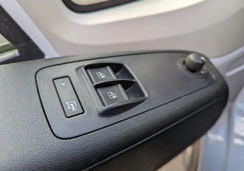 Gros plan sur les commandes de lève-vitres et réglage des rétroviseurs côté conducteur du FIAT Ducato Fourgon blanc 2019.