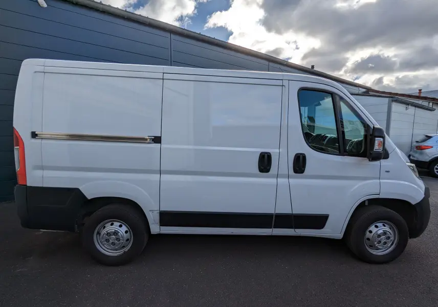 Fiat Ducato Fourgon blanc vu de profil côté gauche, avec portes coulissantes et jantes acier simples.