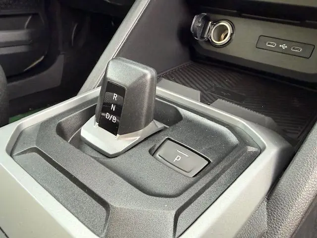 Gros plan sur la commande de boîte automatique et bouton parking du Dacia Duster 1.8 Hybrid 155 Journey, intérieur noir.