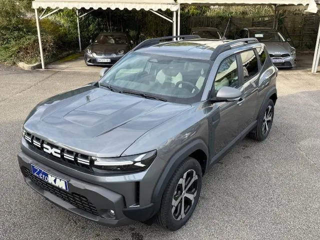 Vue 3/4 avant droite du Dacia Duster 1.8 Hybrid 155 Journey gris schiste avec jantes biton et toit noir.