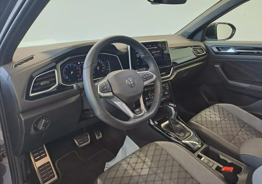 Vue intérieure côté conducteur du Volkswagen T-Roc 2025, volant multifonction et sièges tissu à motifs géométriques.