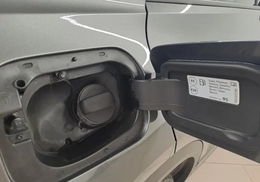 Gros plan sur la trappe à carburant ouverte d'un Volkswagen T-Roc gris Indium avec toit noir, essence, côté gauche arrière.