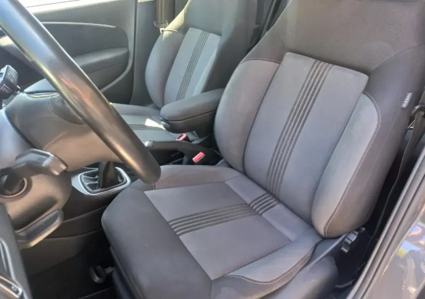 Vue intérieure côté conducteur de la Volkswagen Polo gris 2016, montrant les sièges tissu avec bandes centrales et levier de vitesse manuel.