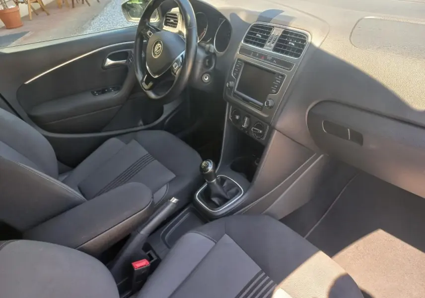 Vue intérieure côté conducteur de la Volkswagen Polo gris 2016, avec volant, tableau de bord et levier de vitesse manuel visibles.