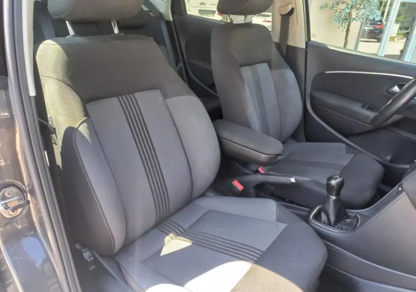 Vue intérieure côté conducteur de la Volkswagen Polo gris 2016, sièges tissu avec bandes centrales et levier de vitesse manuel.