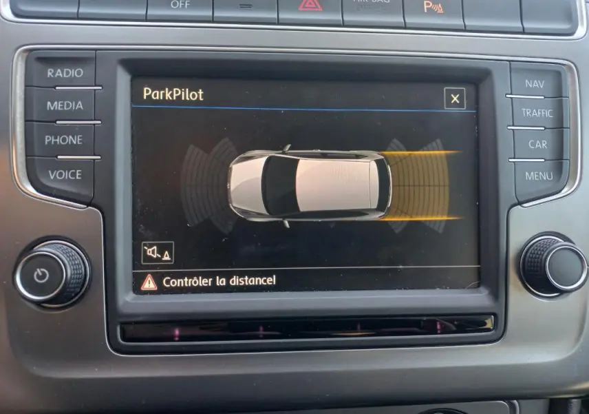 Écran central de la Volkswagen Polo 2016 affichant le système ParkPilot avec vue du véhicule en gris et alertes de distance.