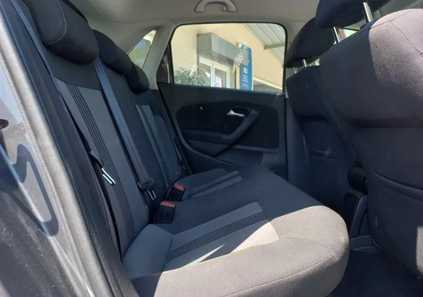 Vue intérieure côté gauche des sièges arrière gris foncé de la Volkswagen Polo 2016 avec ceintures de sécurité visibles.