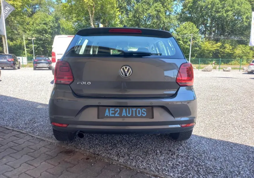 Vue arrière d'une Volkswagen Polo gris 2016, avec feux rouges et plaque AE2 AUTOS visible sur un parking extérieur.