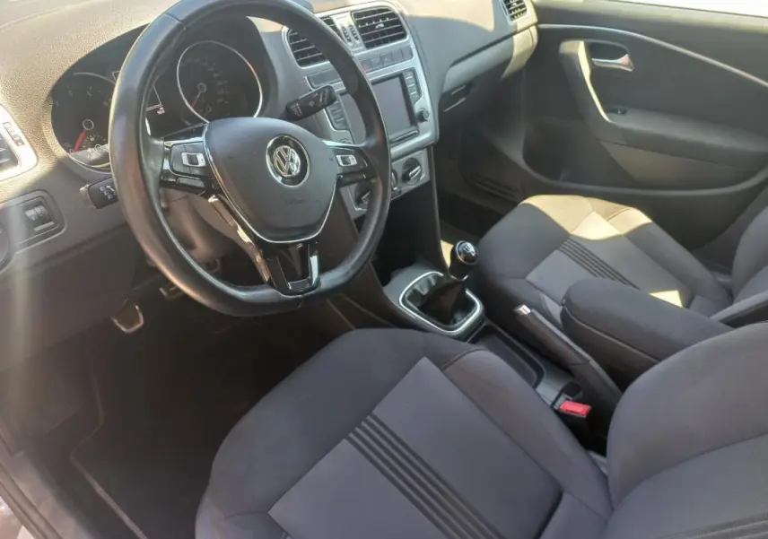 Intérieur de Volkswagen Polo 2016 gris, vue côté conducteur, volant multifonction et levier de vitesse manuel visibles.