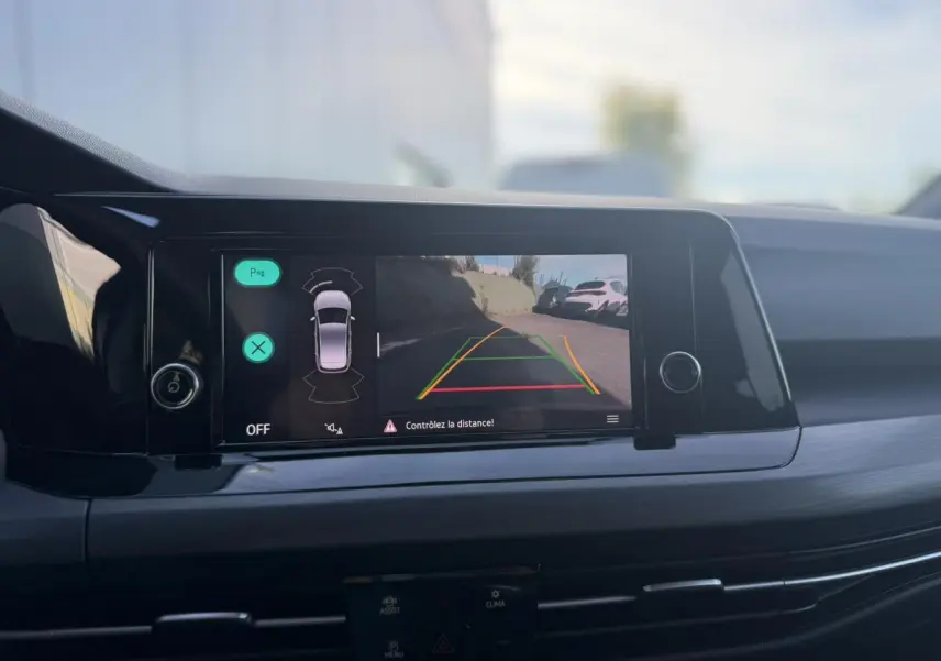 Vue intérieure sur l'écran tactile central affichant la caméra de recul de la Volkswagen Golf VIII noire.