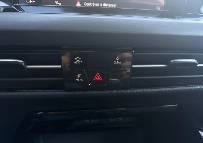 Vue rapprochée du tableau de bord noir de la Volkswagen Golf VIII 2024, avec boutons d'alerte et d'assistance visibles.