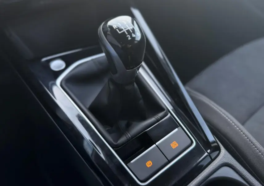 Gros plan sur le levier de vitesses manuel noir et la console centrale brillante de la Volkswagen Golf VIII 1.5 TSI.