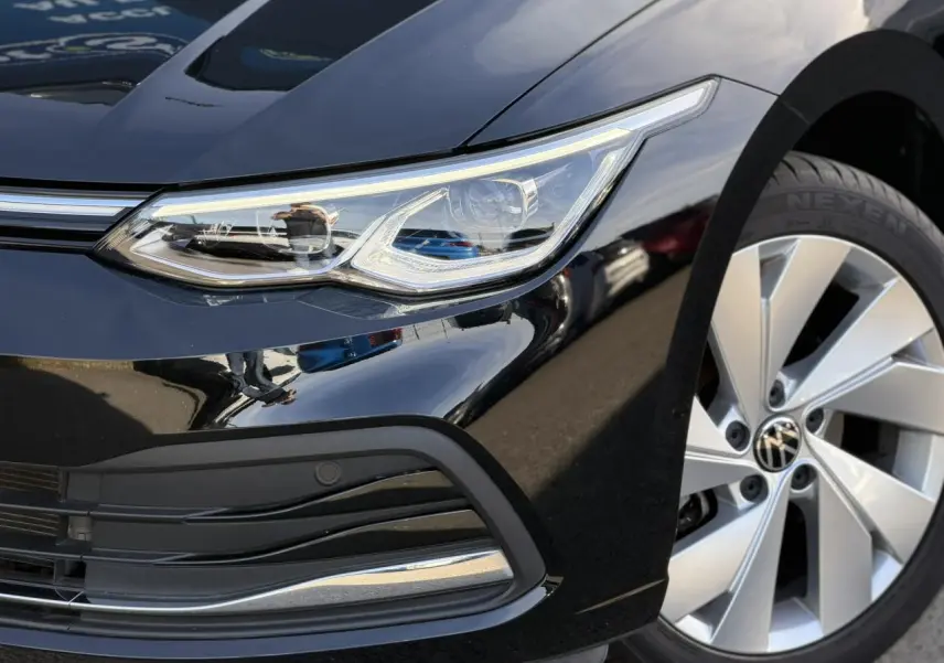 Gros plan sur l'avant droit noir nacré d'une Volkswagen Golf VIII 2024, avec phare LED et jante alliage 17 pouces.