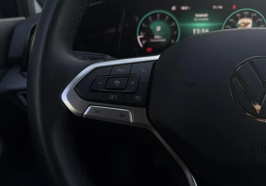Gros plan sur le volant cuir noir de la Volkswagen Golf VIII 2024, avec commandes multifonctions et tableau de bord numérique en arrière-plan.