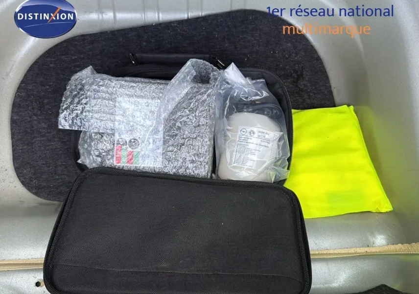 Coffre ouvert d'une Opel Astra Sports Tourer gris minéral, montrant un gilet jaune et une trousse de secours.