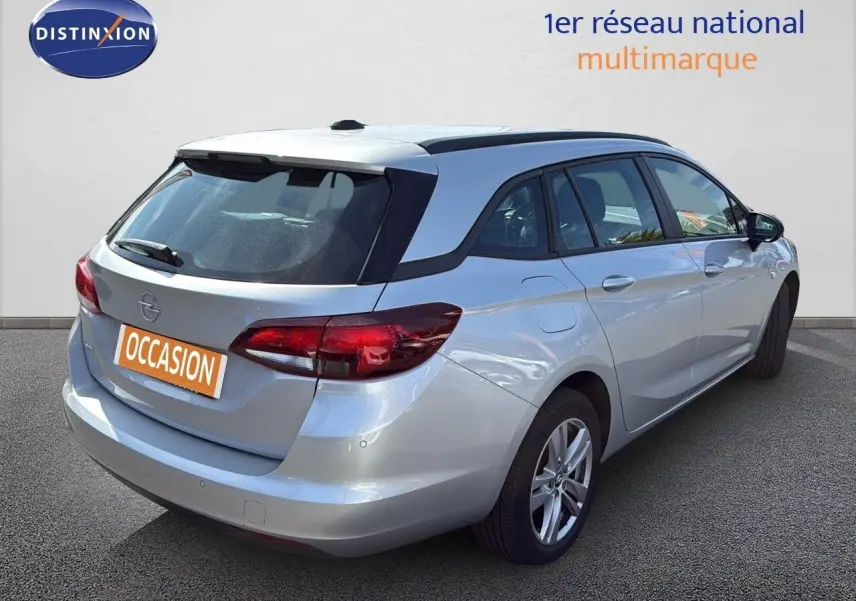 Vue 3/4 arrière droite d'une Opel Astra Sports Tourer gris minéral métal avec feux arrière LED et toit ouvrant.