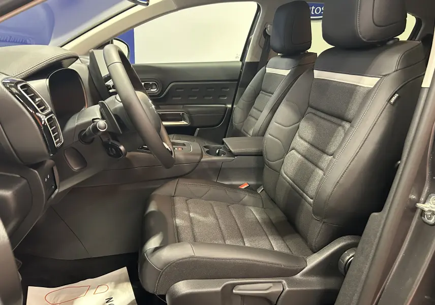 Vue intérieure côté conducteur du Citroën C5 Aircross gris platinium, sièges en cuir noir avec inserts tissu et tableau de bord moderne.