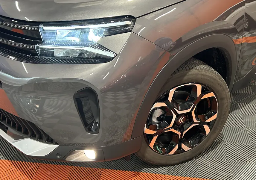 Gros plan sur l'avant droit gris platinium du Citroën C5 Aircross 2025 avec phare LED et jante noire et chrome.