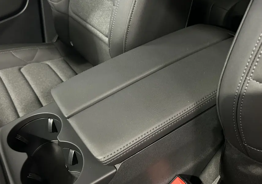 Gros plan sur l'accoudoir central noir et porte-gobelets entre les sièges avant du Citroën C5 Aircross gris platinium.